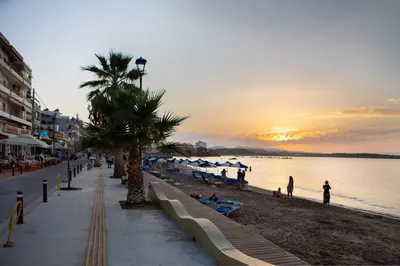 a beach with a palm tree and people on the beach at Casa Gardenia-modern apartment next to the beach, near Old Town in Chania Town