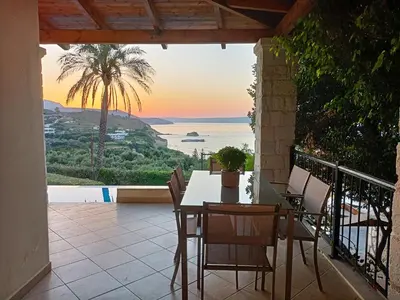 a table and chairs on a balcony with a view of the ocean at Villa Marianne in Chania Town