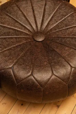a brown leather ottoman sitting on a wooden floor at Beit Petra in Daratso