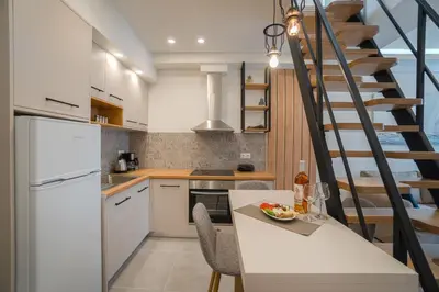 a kitchen with white cabinets and a spiral staircase at Mezoneta 