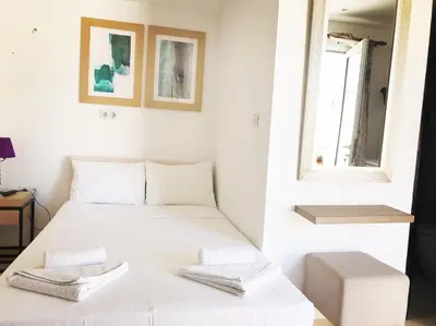 a white bedroom with a bed and a window at Polydoros Hotel Apartments in Palaiochóra