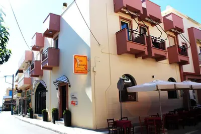 a building with tables and umbrellas on a street at Polydoros Hotel Apartments in Palaiochóra