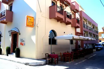 a restaurant with chairs and an umbrella next to a building at Polydoros Hotel Apartments in Palaiochóra