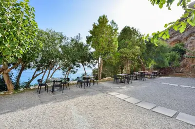 a row of tables and chairs next to the water at Ilingas Mare in Khóra Sfakíon