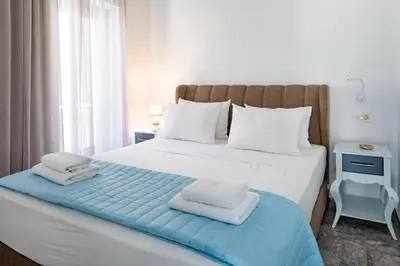 a bedroom with a large white bed with towels on it at Plori - Molos Apartments in Loutro