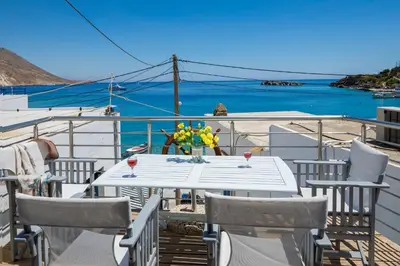 a table and chairs on a balcony with a view of the ocean at Plori - Molos Apartments in Loutro