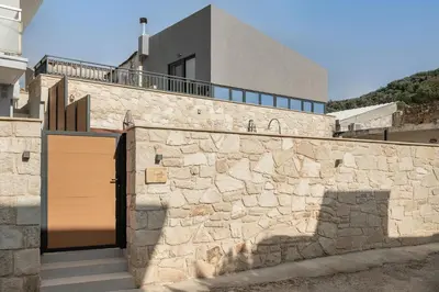 a building with a stone wall with a wooden door at Villa Magnolia in Ayiá