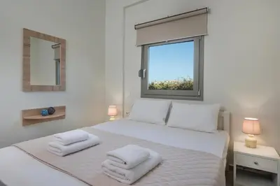 a bedroom with a white bed with towels on it at SEA BREEZE APARTMENTS in Kolymvari