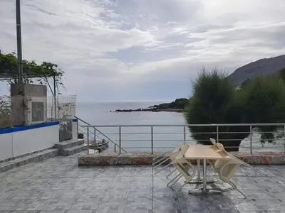 a table and chairs on a patio near a body of water at EDEM HOUSE FINIKAS in Loutro