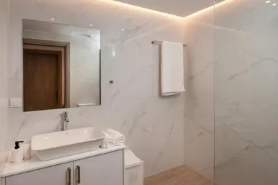 a white bathroom with a sink and a mirror at Thyme Sea View Apartments by 8essentially in Souda