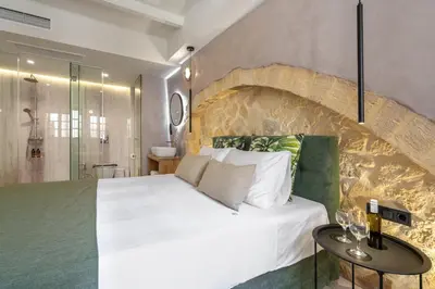 a bedroom with a white bed and a stone wall at Monk Rooms in Chania Town