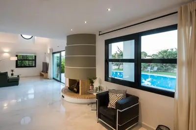 a living room with a fireplace and a large window at Gregorys Private Luxury Villa with Heated Pool & Gardens in SFakianalíon
