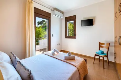 a bedroom with a bed and a window and a chair at Villa Alexandra in Kolymvari