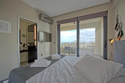a bedroom with a bed with a view of a balcony at Villa Popi - modern villa with private pool by PosarelliVillas in Galatás
