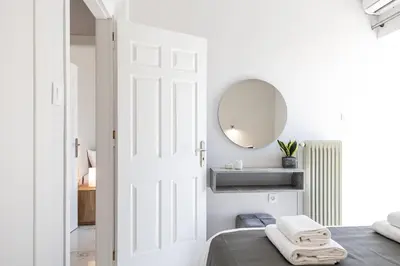 a white bedroom with a bed and a mirror at West City Apartment in Chania Town