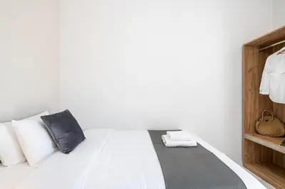 a bedroom with a bed with white sheets and pillows at West City Apartment in Chania Town