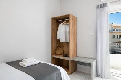 a white bedroom with a bed and a window at West City Apartment in Chania Town