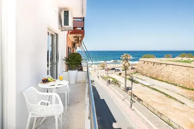 a balcony with a table and chairs and the ocean at West City Apartment in Chania Town
