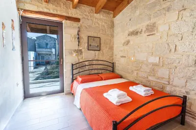 a bedroom with a bed and a stone wall at SpiliaInn in Spiliá