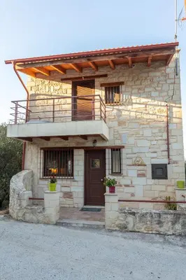 a stone house with a wooden door and a balcony at SpiliaInn in Spiliá