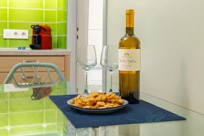 a bottle of wine and a plate of food and two wine glasses at Golden Key apartments in Chania Town