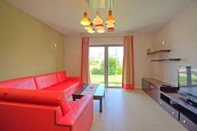 a living room with a red couch and a tv at Cabanavillas Rio by PosarelliVillas in Agia Marina Nea Kydonias