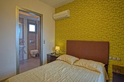 a bedroom with a bed and a yellow wall at Cabanavillas Rio by PosarelliVillas in Agia Marina Nea Kydonias