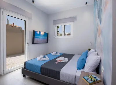a bedroom with a bed with blue pillows and a television at Luxury Villa Eva-Mari with jacuzzi, 50m from the beach in Stalos