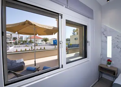 a room with a window with a chair and an umbrella at Luxury Villa Eva-Mari with jacuzzi, 50m from the beach in Stalos