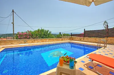 a swimming pool with a table and a chair next to it at Villa Romantic Sevi by PosarelliVillas in Káto Vení