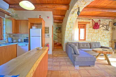 a kitchen and a living room with a couch and a table at Villa Vrisses by PosarelliVillas in Vryses