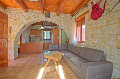 a living room with a couch and a stone wall at Villa Vrisses by PosarelliVillas in Vryses