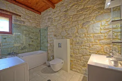 a stone bathroom with a toilet and a sink at Villa Nipos by PosarelliVillas in Vryses