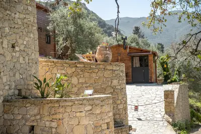 a house with a stone wall next to a building at Wooden House Apts - Between Balos & Elafonissi in Kaláthenai