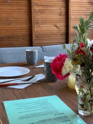 a wooden table with plates and flowers on it at Wooden House Apts - Between Balos & Elafonissi in Kaláthenai