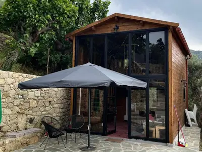 an umbrella sitting in front of a glass house at Wooden House Apts - Between Balos & Elafonissi in Kaláthenai