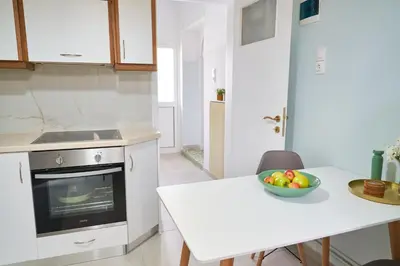 a white kitchen with a table and a bowl of fruit at Philoxenia Residence Chania City Centre in Chania Town