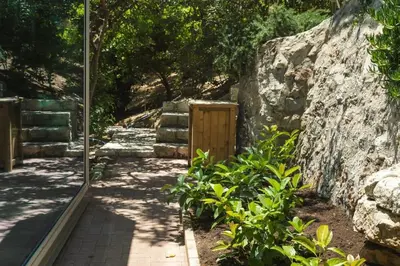 a garden with a stone wall and a walkway at Luxury TreeHouse - A breath away from the beach in Loutrákion