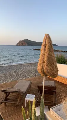 a umbrella and chairs on a beach with the ocean at Esperanto seafront studio in Agia Marina Nea Kydonias