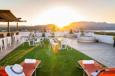 a patio with tables and chairs and the sun setting at Louladakis Apartments in Kolymvari