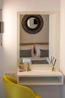 a bedroom with a mirror and a yellow chair at INDIGO BLUE Seaside Deluxe Apartments in Kissamos