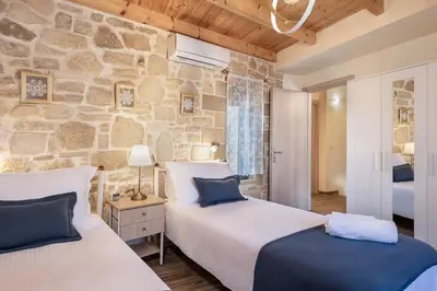 a bedroom with two beds and a stone wall at Villa Vanka in Chania Town
