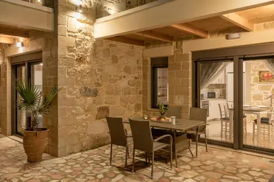 a patio with a table and chairs and a stone wall at Villa Vanka in Chania Town