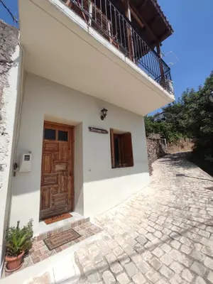 a white house with a wooden door and a balcony at Stefanis traditional house - Kampos in Kámbos