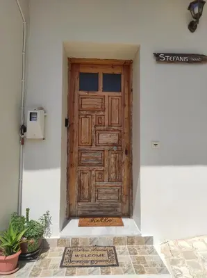 a wooden door on a white wall with a rug at Stefanis traditional house - Kampos in Kámbos