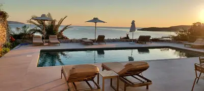 a pool with chairs and umbrellas next to the ocean at Kera Studios in Kalyves