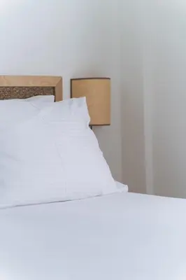 a bed with white sheets and a wooden headboard at Kera Studios in Kalyves