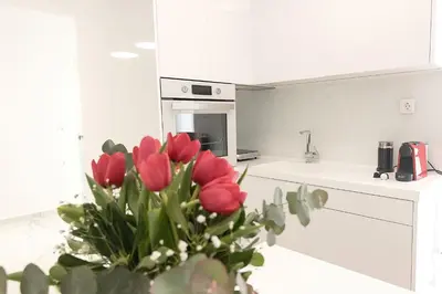 a vase of red tulips in a white kitchen at Aria apts 100 m from the beach by PosarelliVillas in Kolymvari