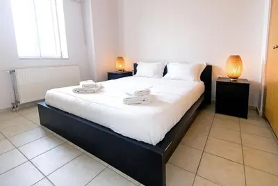 a bedroom with a large white bed with two lamps at Aria apts 100 m from the beach by PosarelliVillas in Kolymvari