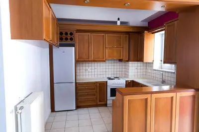 a kitchen with wooden cabinets and a white refrigerator at Aria apts 100 m from the beach by PosarelliVillas in Kolymvari